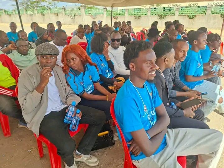 Youth and community members in event t-shirts sitting together at National Youth Day in Kajiado